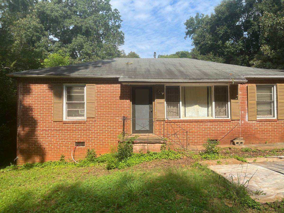 Brick ranch house in Decatur, GA exactly as Mighty Estates bought it, with overgrown yard